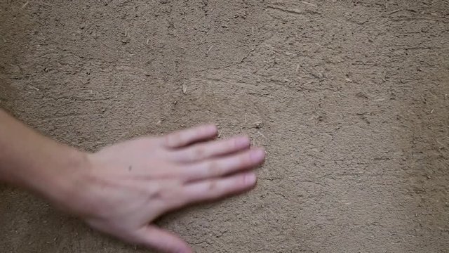 Hand of a young women stroking an environmentally friendly wall with clay plaster