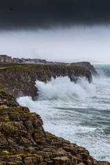 A huge ocean waves breaking on the coastal cliffs in at the cloudy stormy day. Breathtaking romantic seascape of ocean coastline. Peniche, Portugal.