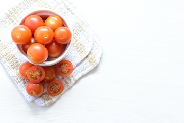 Fresh cherry tomato, displayed in containers on white wooden background