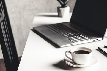 Business man using laptop computer with pen glasses and cup of hot coffee