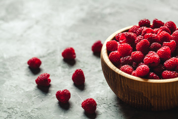raspberries in wood bowl on gray table, vintage