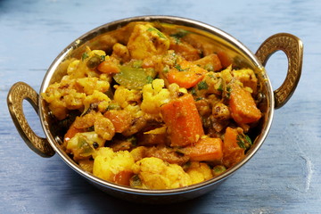 Mixed vegetable curry in a dish on a wooden blue background, with copy space.