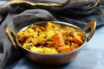 Mixed vegetable curry in a dish on a wooden blue background, with copy space.