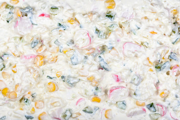 Salad with egg, canned corn, crab sticks, fresh cucumber and mayonnaise. Texture © Olga Makukha