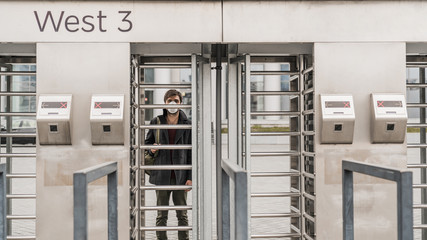 Young man in protection mask near closed enter gate to stadium. European coronavirus.