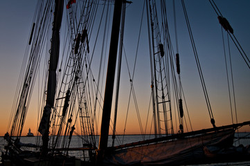 Sunrise over Lake Michigan viewed through the riggings of the tall ship Roseway moored at Navy Pier.  Chicago, Illinois, USA.