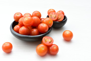 Fresh cherry tomato, displayed in containers on white wooden background