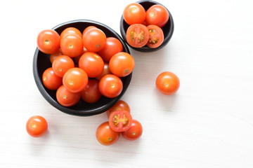 Fresh cherry tomato, displayed in containers on white wooden background