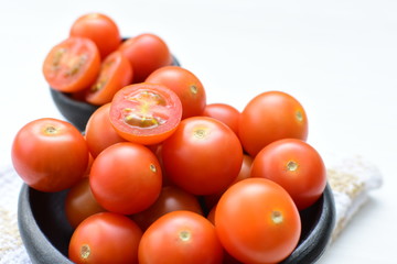 Fresh cherry tomato, displayed in containers on white wooden background