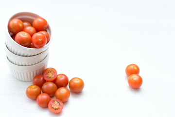 Fresh cherry tomato, displayed in containers on white wooden background