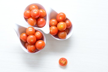Fresh cherry tomato, displayed in containers on white wooden background