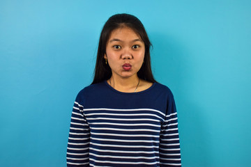 Fototapeta premium Portrait of Young beautiful asian women with blue isolated background, lips folded for kiss