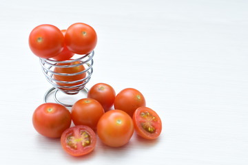 Fresh cherry tomato, displayed in containers on white wooden background