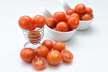Fresh cherry tomato, displayed in containers on white wooden background