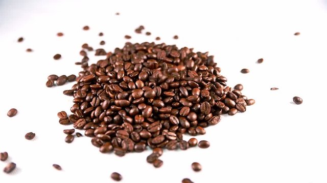 Coffee beans dropping onto a white isolated background