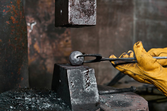 machine hammer turns into a sphere a metal workpiece held by a blacksmith with pincers