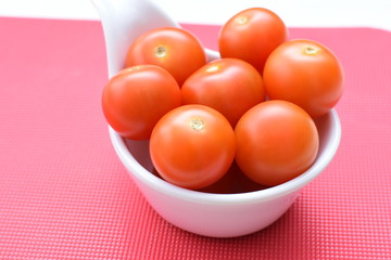 Fresh cherry tomato, displayed in containers on colorful colors background