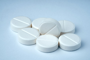 Closeup of white pills on a white background with texture.