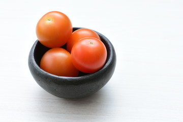 Fresh cherry tomato, displayed in containers on white wooden background