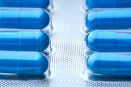 Closeup of some blue pills in packaging.