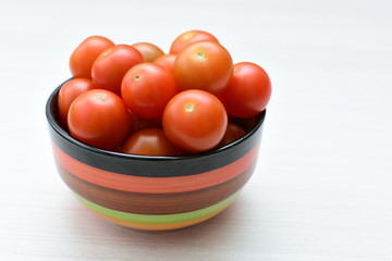 Fresh cherry tomato, displayed in containers on white wooden background