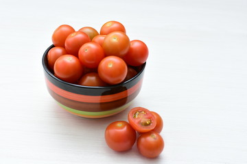 Fresh cherry tomato, displayed in containers on white wooden background