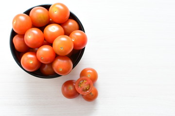 Fresh cherry tomato, displayed in containers on white wooden background