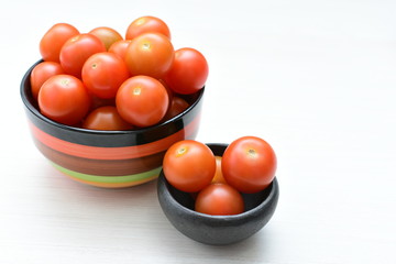 Fresh cherry tomato, displayed in containers on white wooden background