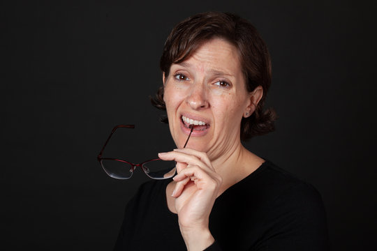 Woman in black holding glasses in her mouth