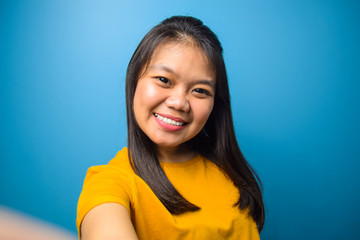 Portrait of Young beautiful asian women with blue isolated background, taking selfie