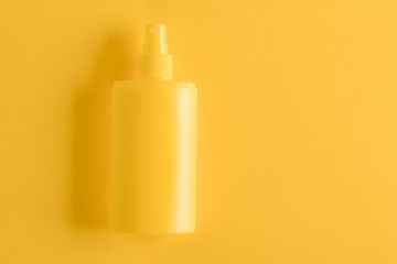 Sunscreen spray on yellow background
