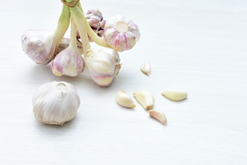 Heads of garlic, ripe white corsage on white wooden background