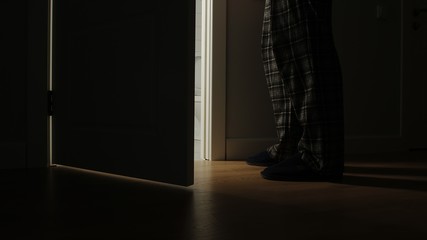 Adult man in a pajamas walks to a bathroom in the night