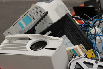 a pile of plastic technology waste and used broken office equipment heaped in a rubbish bin being taken for disposal