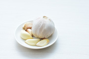 Heads of garlic, ripe white corsage on white wooden background