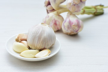 Heads of garlic, ripe white corsage on white wooden background
