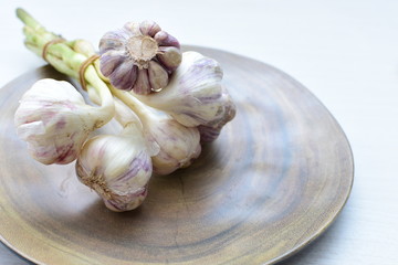 Heads of garlic, ripe white corsage on white wooden background
