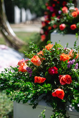 Wedding decorations with beautiful flowers red and yellow roses for ceremony outdoors. Summer floral composition. Elegant arrangement floristics setting. Party decor detail