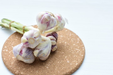 Heads of garlic, ripe white corsage on white wooden background