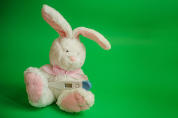 Toy Hare with electronic thermometer under paw. Measuring high temperature of children with influenza and viruses, coronavirus. Medicine concept.