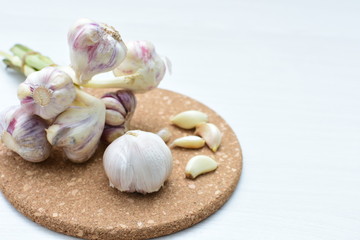Heads of garlic, ripe white corsage on white wooden background