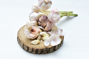 Heads of garlic, ripe white corsage on white wooden background