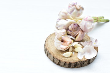 Heads of garlic, ripe white corsage on white wooden background