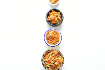 Petals of chopped dried calendula, displayed in containers on white wooden background