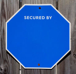 Blank blue octagonal security sign mounted on fence. Copy space.