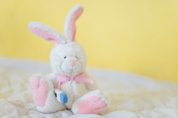 Toy Hare with electronic thermometer under paw. Measuring high temperature of children with influenza and viruses, coronavirus. Medicine concept.