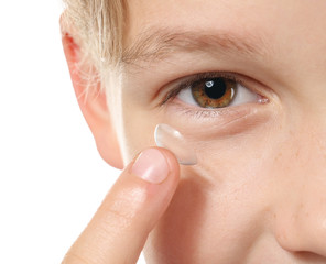 Little boy putting in contact lens on white background, closeup