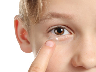 Little boy putting in contact lens on white background, closeup