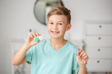 Little boy with contact lens case and eyeglasses at home