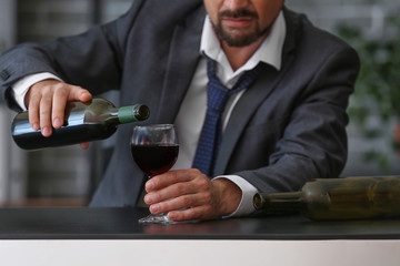 Businessman drinking wine in office. Concept of alcoholism
